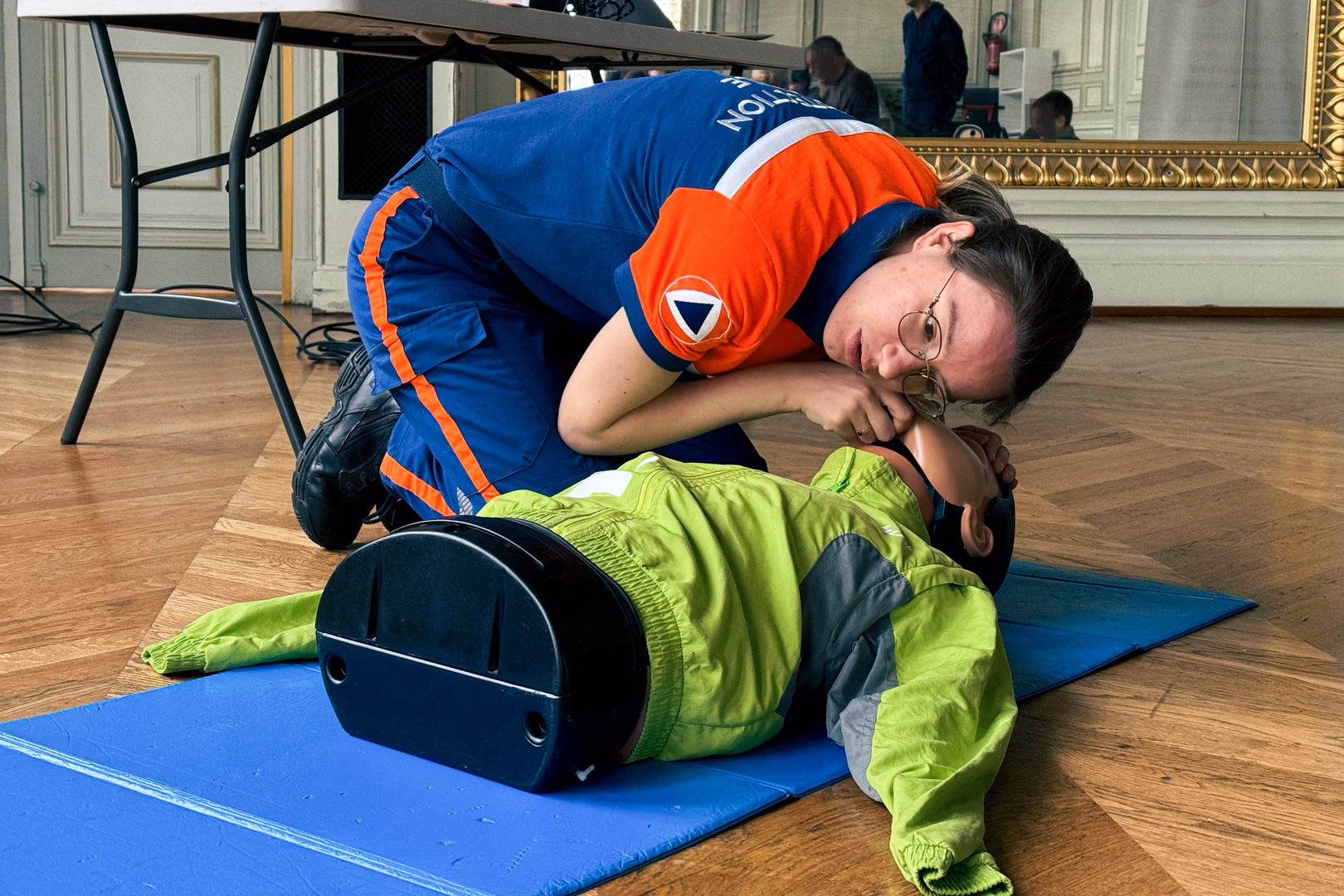 Une formatrice premiers secours de la protection civile paris 6&7 explique le massage cardiaque à un public à la mairie du 6ème arrondissement.